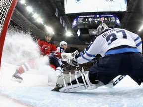Winnipeg Jets' goaltender Connor Hellebuyck stops Brian Boyle of the New Jersey Devils during NHL action Thursday night in Newark, N.J.  Hellebuyck made 41 saves in a 3-2 victory to establish a new franchise record.