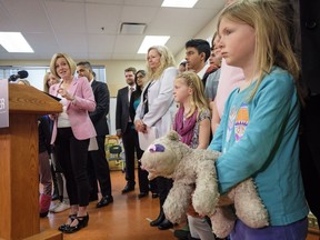 Premier Rachel Notley, left, speaks at an event announcing new schools as a young girl holds a teddy bear in Calgary, Alta., Friday, March 23, 2018.THE CANADIAN PRESS/Jeff McIntosh