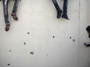 Palestinians check bullet holes in a wall following an exchange of gunfire between Palestinian Hamas security forces and suspects wanted for a bombing that targeted the visiting Palestinian premier's convoy last week in Gaza, in the town of Nuseirat, central Gaza Strip, Thursday, March 22, 2018.