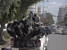 Masked militants from the Izzedine al-Qassam Brigades, a military wing of Hamas, ride in the back of a truck with their weapons, during a large-scale drill across the Gaza strip, Sunday, March 25, 2018.