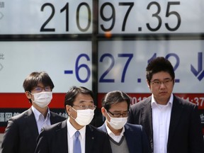 People walk by an electronic stock board of a securities firm in Tokyo, Friday, March 2, 2018. Asian shares posted steep declines Friday, adding to global stock market losses after President Donald Trump vowed to impose stiff steel and aluminum tariffs, sparking fears of a trade war.