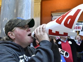 CORRECTS FIRST NAME FROM NEMIA TO NEMA - Nema Brewer, an employee of the Fayette County School District, uses a protest sign as a makeshift bullhorn to shout at the Kentucky Senate chambers in protest of Kentucky Senate Bill 1, Friday, March 9, 2018, in Frankfort, Ky.