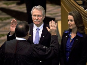FILE - In this Jan. 12, 2015, file photo, Oregon Gov. John Kitzhaber, left, is joined by his fiancee, Cylvia Hayes, as he is sworn in for an unprecedented fourth term in Salem, Ore. The Oregon Government Ethics Commission has voted to accept a settlement with former Gov. Kitzhaber that requires him to pay a $20,000 fine for violating state ethics laws. Kitzhaber attended a meeting Friday, March 30, 2018, in Salem and expressed regret for his mistakes, The Statesman Journal reported.
