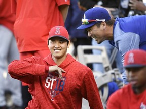 Angeles Angels' Shohei Ohtani, left, of Japan, talks with Los Angeles Dodgers' Kenta Maeda, right, also of Japan, as he stretches prior to a preseason baseball game Monday, March 26, 2018, in Los Angeles.