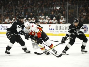 Calgary Flames' Mikael Backlund, center, of Sweden, is defended by Los Angeles Kings' Derek Forbort, left, and Trevor Lewis during the first period of an NHL hockey game Monday, March 26, 2018, in Los Angeles.