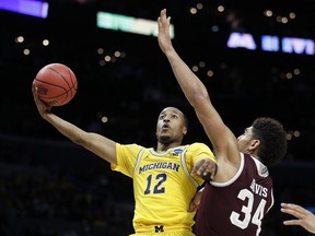 Michigan guard Muhammad-Ali Abdur-Rahkman (12) shoots as Texas A&M center Tyler Davis (34) defends during the first half of an NCAA men's college basketball tournament regional semifinal Thursday, March 22, 2018, in Los Angeles.