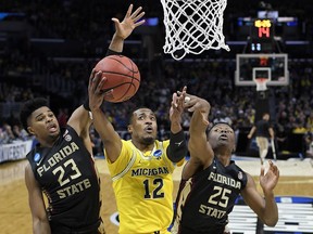 Michigan guard Muhammad-Ali Abdur-Rahkman (12) shoots between Florida State guard M.J. Walker (23) and forward Mfiondu Kabengele (25) during the first half of an NCAA men's college basketball tournament regional final Saturday, March 24, 2018, in Los Angeles.