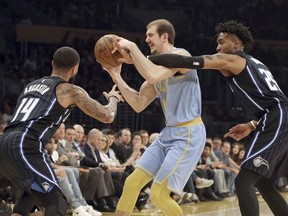 Los Angeles Lakers guard Alex Caruso (4) is defended by Orlando Magic guard Brandon Ingram (14) and forward Wes Iwundu (25), who fouls Caruso during the first half of an NBA basketball game in Los Angeles on Wednesday, March 7, 2018.