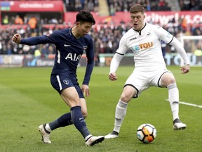 Tottenham Hotspur's Son Heung-Min, left, and Swansea City's Alfie Mawson battle for the ball during the English FA Cup, quarterfinal soccer match at the Liberty Stadium, Swansea, Wales, Saturday March 17, 2018.