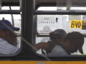 Bus passengers sleep as they make their way past Congress in Lima, Peru, Thursday, March 22, 2018. Peru's congress is gearing up to consider whether or not to accept President Pedro Pablo Kuczynski's resignation following the release of several videos appearing to show allies offering state contracts in exchange for votes against his pending impeachment.