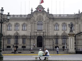 A couple sit on a bench in front of Government Palace also known as the House of Pizarro, in Lima, Peru, Wednesday, March 21, 2018. Pressure is building on Peru's President Pedro Pablo Kuczynski to resign after several allies were caught in secretly-shot videos allegedly trying to buy the support of a lawmaker so he would block the leader's impeachment.