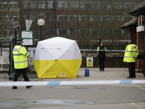 Police officers guard a cordon around a police tent covering a supermarket car park pay machine near the area where former Russian double agent Sergei Skripal and his daughter were found critically ill following exposure to the Russian-developed nerve agent Novichok in Salisbury, England, Tuesday, March 13, 2018.