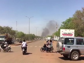 Smoke rises in the background in Ouagadougou, Burkina Faso in this image taken from video Friday March 2, 2018.  Gunfire and explosions rocked Burkina Faso's capital early Friday in what the police said was a suspected attack by Islamic extremists. By midday the gunfire became intermittent and helicopters flew above the French Embassy in Ouagadougou.(AP Photo)