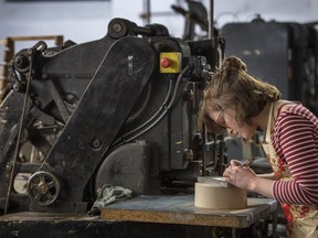 Lottie Small cuts the crests being used on the invitations for Prince Harry and Meghan Markle's wedding in May, at the workshop of Barnard and Westwood in London Thursday March 22, 2018. Prince Harry and Meghan will get married at St George's Chapel  in Windsor Castle on Saturday  May 19.