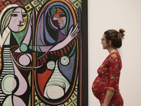 A woman looking at Pablo Picasso's Girl before a Mirror, 1932, during a preview of the exhibition Picasso 1932 - Love, Fame, Tragedy at Tate Modern in London, Tuesday March 6, 2018.  The first ever solo Pablo Picasso exhibition remains at Tate Modern for the summer.