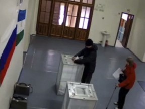 In this screen grab taken from video provide by the Central Election Commision (CEC) via Navalny Opposition Group on Sunday, March 18, 2018 in Tambov, Russia, a man allegedly stuffs ballots into a ballot box at a polling station. Russian election officials say they are looking into several incidents of ballot stuffing in the presidential vote. (Navalny Opposition Group via AP)