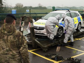 In this image dated Friday March 9, 2018, and issued Saturday March 10, 2018, by Britain's Ministry of Defence, showing troops in protective gear as they work to remove a contaminated police car from the Accident and Emergency entrance at the District Hospital in Salisbury, England. Counter-terrorism police asked for military assistance to remove vehicles and objects from the scene in the city, much of which has been cordoned off over contamination fears of the nerve agent poisoning of former spy Sergei Skripal and his daughter.