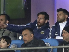 Lionel Messi, centre, and Sergio Aguero are seen in the stands during the international friendly soccer match between Argentina and Italy at the Etihad Stadium in Manchester, England, Friday March 23, 2018.