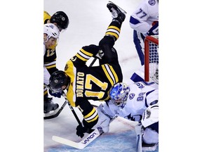 Boston Bruins center Ryan Donato (17) is upended as he collides with Tampa Bay Lightning goaltender Andrei Vasilevskiy (88) during the first period of an NHL hockey game in Boston, Thursday, March 29, 2018.