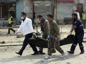 Security personnel carry a body at the site of a suicide attack in Kabul, Friday, March 9, 2018. A suicide bomber targeting Afghanistan's minority Hazaras blew himself up at a police checkpoint in western Kabul on Friday, killing nine people and wounding more than a dozen, officials said.