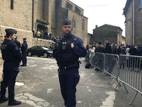 Police officers stand guard outside the Saint-Etienne-de-Trebes church in Trebes, southern France, Sunday, March 25, 2018, as people arrive for a special church service to honor the heroic police officer and three others killed in a rampage by an Islamic extremist.