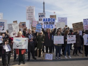 People hold banners during the "March For Our Lives" event in Paris, France, Saturday, March 24, 2018. The march is one of hundreds happening across the U.S. and the world to urge U.S. lawmakers to pass stricter gun safety legislation after deadly school shootings.