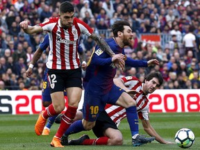 FC Barcelona's Lionel Messi, center, duels for the ball against Athletic Bilbao's Unai Nunez, left, during the Spanish La Liga soccer match between FC Barcelona and Athletic Bilbao at the Camp Nou stadium in Barcelona, Spain, Sunday, March 18, 2018.