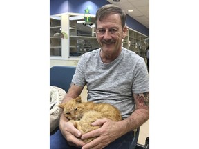 This March 2018 photo made available by the Humane Society of the Treasure Coast in Palm City, Fla., shows Perry Martin with his cat T2. Martin lost his pet during Hurricane Jeanne 14 years ago. Martin had T2 implanted with a microchip in 2002. He never heard any news about his missing pet until a Martin County Animal Services officer called him to tell him T2 was in a shelter in Palm City.