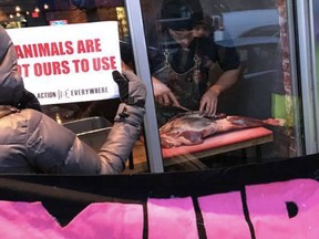 Michael Hunter, owner-chef of Antler Kitchen and Bar in Toronto, butchers a deer leg while vegans protest outside on Friday March 23, 2018.