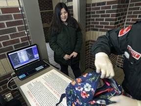 In a photo from Thursday, March 8, 2018, in Detroit, Alondra Alvarez, a student at Western International High School, goes through a metal detector and has her backpack checked as she enters the school. Experts say metal detectors and other security measures put in place decades ago to quell gang and other violence in many urban schools have made them tough targets for mass shootings by troubled students or outsiders.