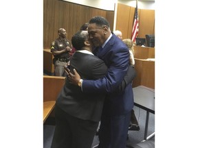 Richard Phillips, right,  hugs Det. Patricia Little in a Wayne County, Mich., courtroom on Wednesday, March 28, 2018, in Detroit. Phillips, a Michigan man whose murder conviction was thrown out after he spent 45 years in prison will not face a second trial.