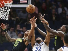 Minnesota Timberwolves forward Karl-Anthony Towns (32) vies for a rebound with Atlanta Hawks forwards Dewayne Dedmon (14) and John Collins (20) during the first quarter of an NBA basketball game Wednesday, March 28, 2018, in Minneapolis.