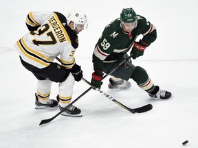 Boston Bruins' Patrice Bergeron (37) and Minnesota Wild's Zack Mitchell (59) skate after the puck during the first period of an NHL hockey game Sunday, March 25, 2018, in St. Paul, Minn.