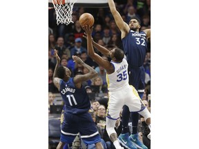 Golden State Warriors' Kevin Durant, center, shoots between Minnesota Timberwolves' Jamal Crawford, left, and Karl-Anthony Towns in the first half of an NBA basketball game Sunday, March 11, 2018, in Minneapolis.