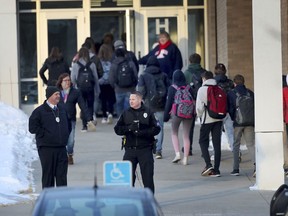 In this Feb. 22, 2018 photo, police officers stand guard as Orono High School students arrive for school, one day after a threat was posted, causing the school to go on lockdown in Orono, Minn. An autistic Orono High School student whose alleged threat led to a six-hour lockdown is in juvenile court. He's received an outpouring of sympathy, and donations for his family. The Feb. 14 killings of 17 people in Parkland, Fla., ignited the usual copycat threats.