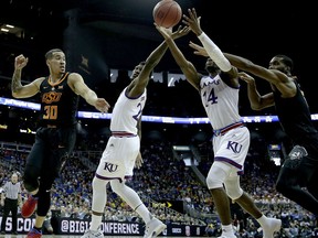 Oklahoma State's Jeffrey Carroll (30), and Tavarius Shine, left, battle Kansas' Silvio De Sousa (22) and Malik Newman (14) for a rebound during the first half of an NCAA college basketball game in the Big 12 conference tournament Thursday, March 8, 2018, in Kansas City, Mo.