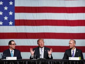 Treasury Secretary Steve Mnuchin, left, and Boeing CEO Dennis Muilenburg, right, listens as President Donald Trump speaks during a roundtable discussion on tax policy at the Boeing Company, Wednesday, March 14, 2018, in St. Louis.