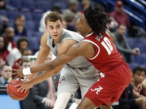 Texas A&M's D.J. Hogg, right, looks to pass around Alabama's Herbert Jones (10) during the first half in an NCAA college basketball game at the Southeastern Conference tournament Thursday, March 8, 2018, in St. Louis.