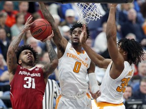 Arkansas' Anton Beard (31) shoots as Tennessee's Jordan Bone (0) and Yves Pons, right, defend during the first half of an NCAA college basketball semifinal game at the Southeastern Conference tournament Saturday, March 10, 2018, in St. Louis.