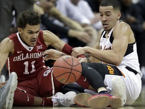 Oklahoma guard Trae Young (11) goes to the floor for a loose ball with Oklahoma State guard Jeffrey Carroll, right, during the first half of an NCAA college basketball game in first round of the Big 12 men's tournament in Kansas City, Mo., Wednesday, March 7, 2018.