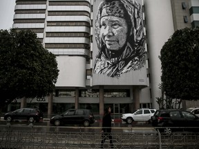 In this Wednesday, March 7, 2018 photo, cars drive past a large mural a Moroccan woman, in Rabat, Morocco.