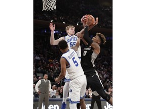 Xavier's J.P. Macura (55) and Trevon Bluiett (5) defend Providence's Nate Watson (0) during overtime of an NCAA college basketball game in the Big East men's tournament semifinals Friday, March 9, 2018, in New York.