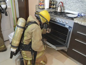 In this undated photo provided by the Quintana Roo Prosecutors Office, a firefighter examines a gas stove in the rented condo where an Iowa couple and their two children died in Tulum, Mexico. Mexican authorities said on Saturday, March 24, 2018 that autopsies indicate the Iowa couple and their two children died from inhaling toxic gas at the rented condo on Mexico's Caribbean coast, but there was no sign of foul play or suicide. (Quintana Roo Prosecutor's Office via AP)