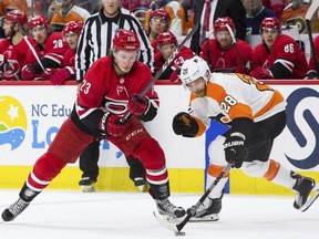 Philadelphia Flyers' Claude Giroux (28) reaches for the puck ahead of Carolina Hurricanes' Brock McGinn (23) during the second period of an NHL hockey game in Raleigh, N.C., Saturday, March 17, 2018.