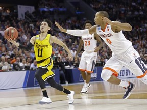 UMBC's K.J. Maura (11) drives past Virginia's Devon Hall (0) during the second half of a first-round game in the NCAA men's college basketball tournament in Charlotte, N.C., Friday, March 16, 2018.