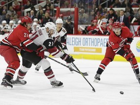 Arizona Coyotes' Derek Stepan (21) chasse the puck with Carolina Hurricanes' Justin Faulk (27) and Valentin Zykov (73) during the first period of an NHL hockey game in Raleigh, N.C., Thursday, March 22, 2018.