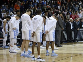 North Carolina team members and fans stand for a moment of silence to honor former UNC radio announcer Woody Durham, who died earlier this week, before the team's NCAA college basketball game against Syracuse in the second round of the Atlantic Coast Conference men's tournament Wednesday, March 7, 2018. in New York.