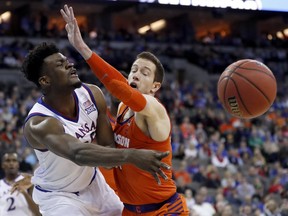 Kansas' Udoka Azubuike, left, passes around Clemson's David Skara during the first half of a regional semifinal game in the NCAA men's college basketball tournament Friday, March 23, 2018, in Omaha, Neb.