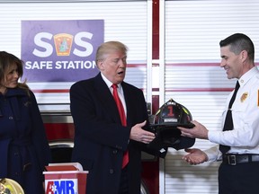 President Donald Trump, center, receives a helmet from Manchester City Fire Chief Daniel Goonan, right, as first lady Melania Trump, left, watches during a visit to the Manchester Central Fire Station in Manchester, N.H., Monday, March 19, 2018. Trump is in New Hampshire to unveil more of his plan to combat the nation's opioid crisis.