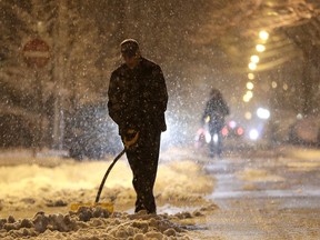 A man shovels the street near the entrance to a firefighter station during a snowstorm, Wednesday, March 21, 2018, in Jersey City, N.J. A spring nor'easter targeted the Northeast on Wednesday with strong winds and a foot or more of snow expected in some parts of the region.